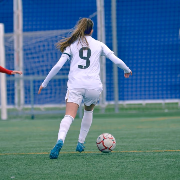 Dolores Delgado conduce la pelota con la camiseta número 9 del Real Madrid en categorías formativas